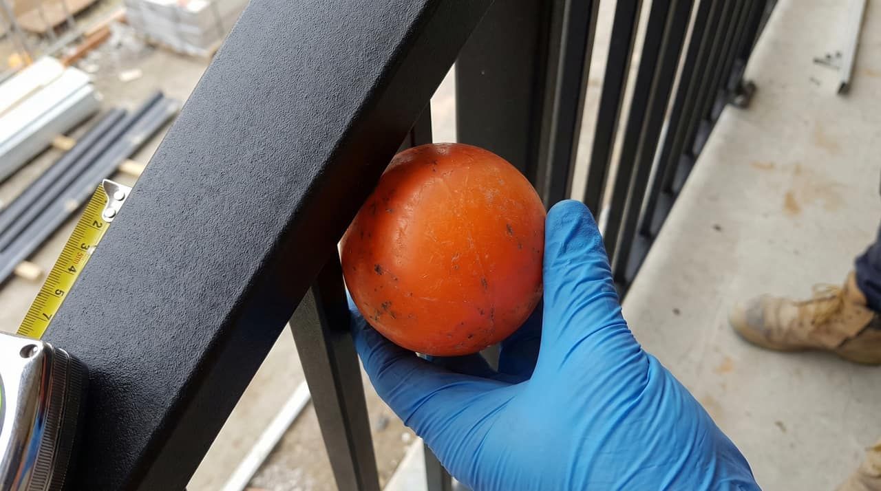 100mm sphere test being performed on steel picket railing to verify BC Building Code compliance