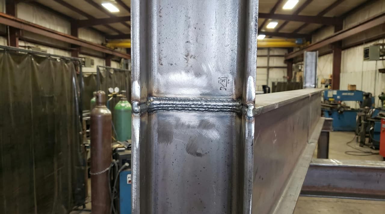 Close-up of a C.W.B. certified weld on a structural steel connection in a fabrication shop